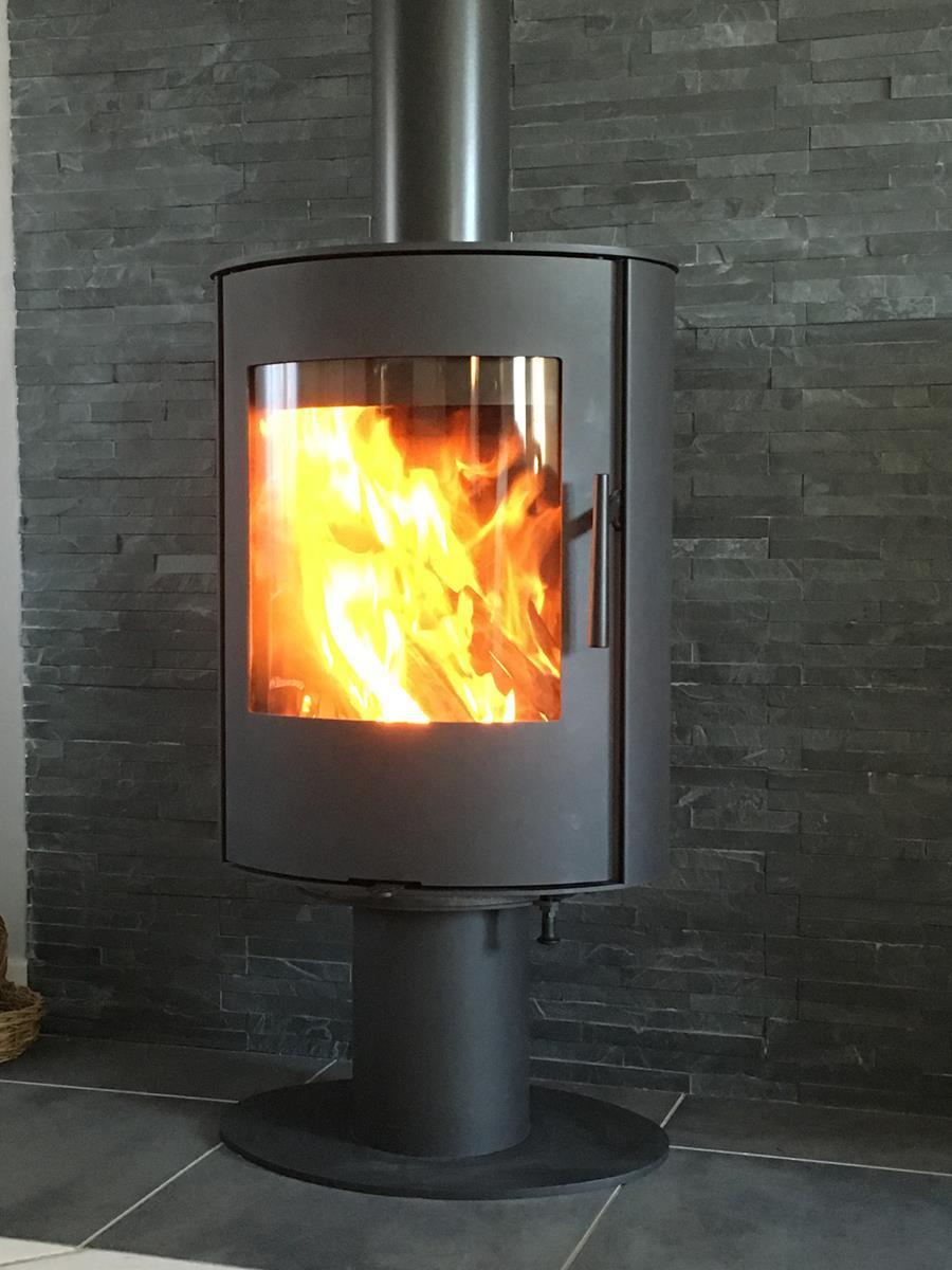 Installation d'un poêle à bois ROMOTOP Evora T, finition acier, appareil pivotant à 360°, dimensions compactes et puissance réduite pour s'adapter aux besoins des maisons basse consommation.